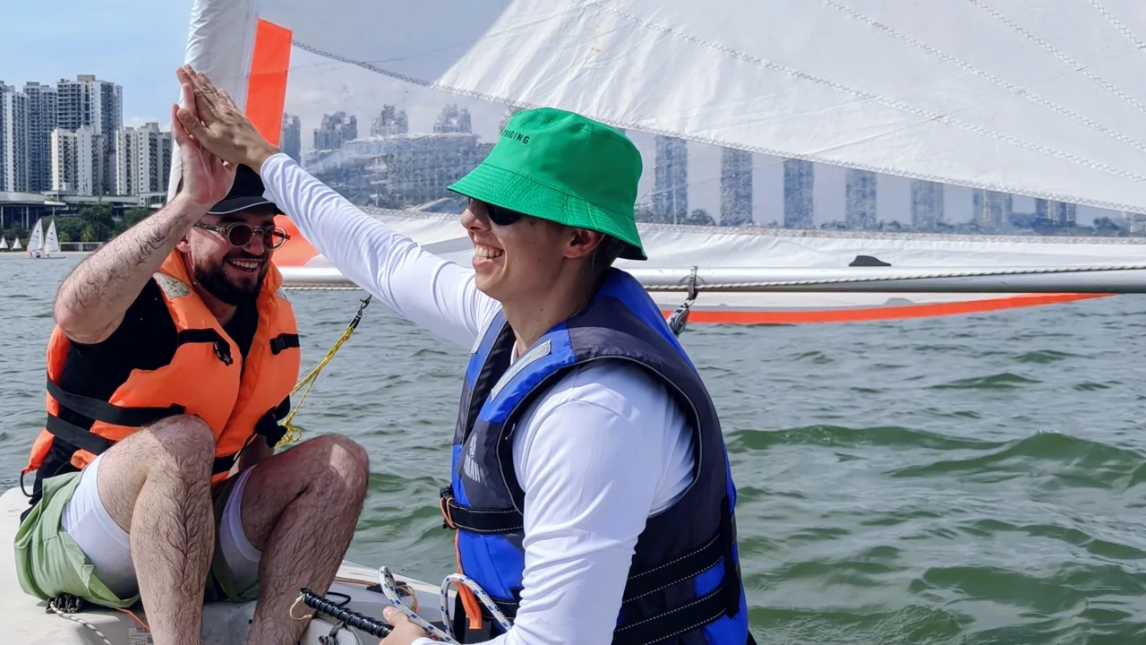 A SeaQuest instructor coaching a young sailor on the water